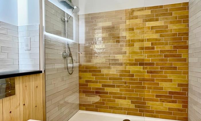 A bright modern shower room with glass screen and colourful tiles.